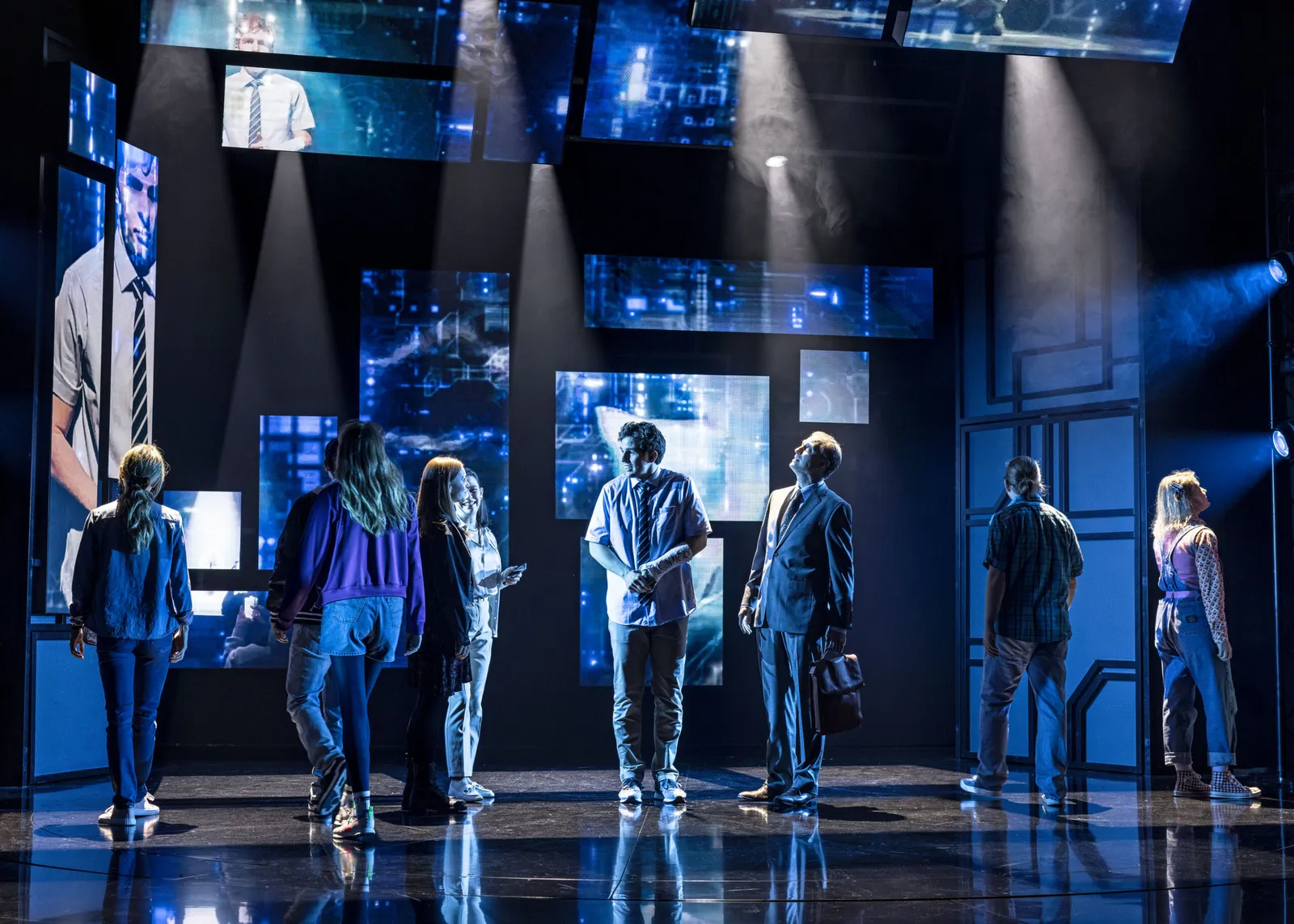 Ensemblen i Dear Evan Hansen på en blåbelyst scen med videoskärmar